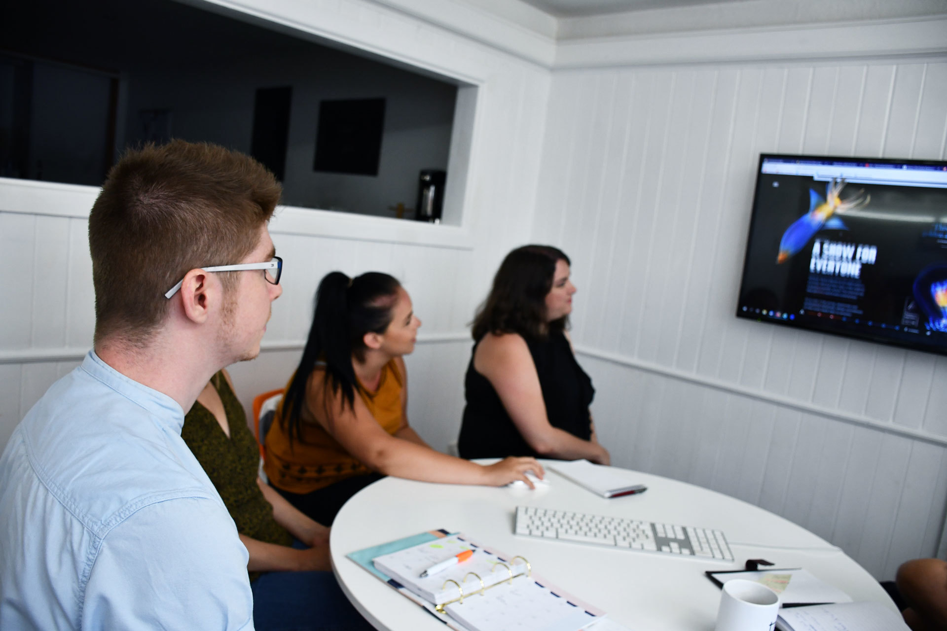 Three staff members looking at a presentation on the television screen